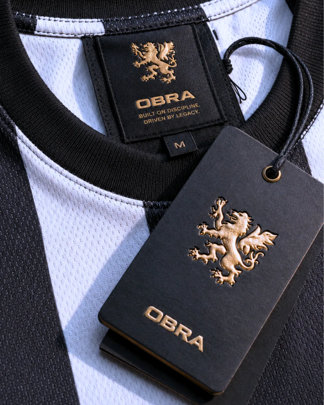 OBRA jersey collar label and swing tag with a gold lion crest