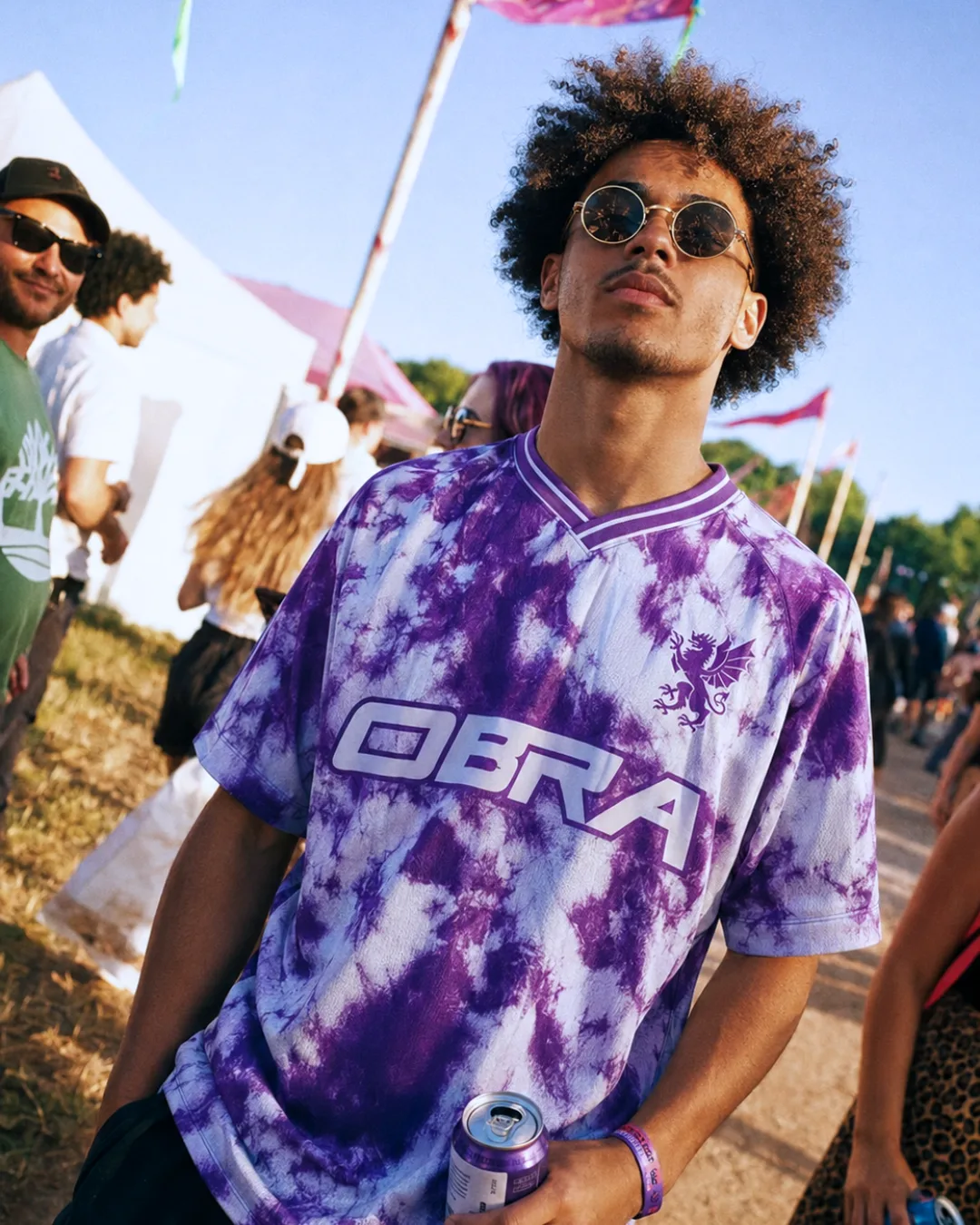 A festival-goer wearing a purple tie-dye OBRA football shirt with the griffin crest